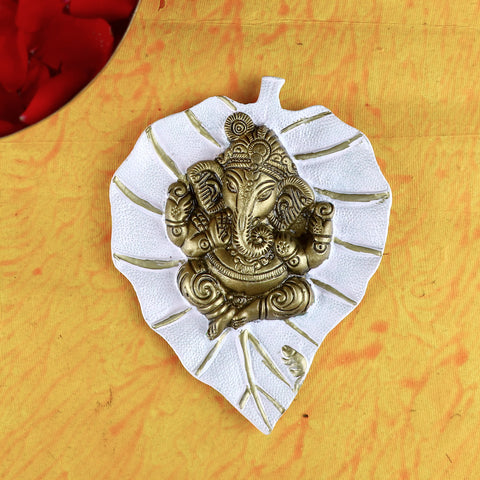 Elegant white leaf-shaped wall hanging featuring a serene idol of Lord Ganesh, ideal for enhancing spiritual ambiance and home decoration. India’s Largest Pooja Accessories Brand – www.satvikstore.in
